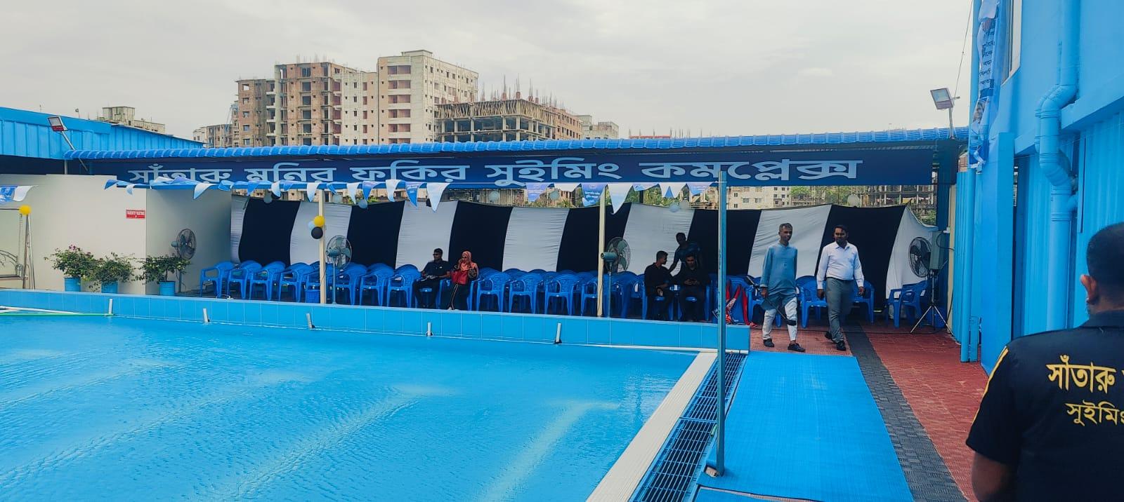 Rows of empty blue chairs wait under a striped canopy beside the pool ahead of the ceremony.